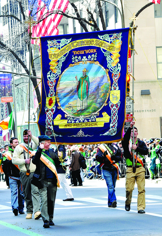 HONORING THE PAST—Celtic scrollwork surrounds image of St. Patrick on resplendent County Tyrone Society banner. Irish county societies usually carry ornate banners depicting saints and heroes.