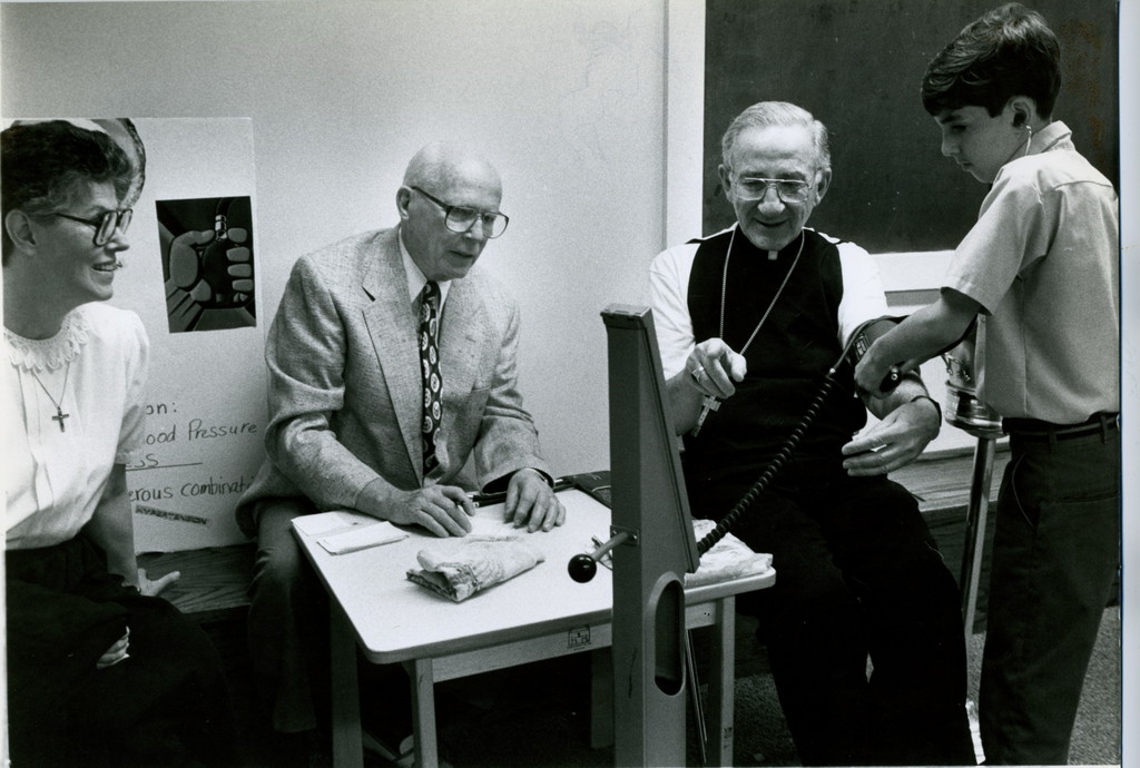 HEALTHY SIGN-Auxiliary Bishop Anthony F. Mestice, who was then pastor of Resurrection parish in Rye, watches the mercury fall as fifth-grader Denny Donovan, right, measures his blood pressure in the parish school's science center. Sister Kathleen Finnerty, O.S.F., principal of the school in 1995, and George Doty, major benefactor for the $350,000 project, which included renovations to the school library. Bishop Mestice, who was also vicar of Central Westchester, blessed the facilities, May 25 1995.