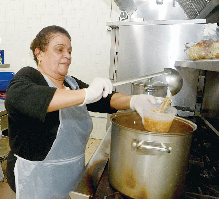 SOUP’S ON—Carmen Santiago, a volunteer cook at Immaculate Conception parish on East Gun Hill Road in the Bronx, ladles up a big bowl of chicken soup to serve to guests at the parish’s soup kitchen last week. Ms. Santiago said that the number of people the soup kitchen serves has increased dramatically in the last few months and that basic food supplies are running low.