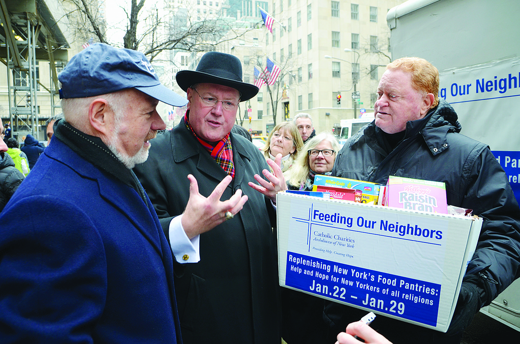 PERSONAL DELIVERY—Cardinal-designate Dolan and Msgr. Kevin Sullivan, executive director of Catholic Charities, hand a large box of groceries to former Mets great Rusty Staub for his mobile food pantry outside St. Patrick’s Cathedral Jan. 22. Feeding Our Neighbors is an archdiocesan campaign to stock food pantries and soup kitchens.