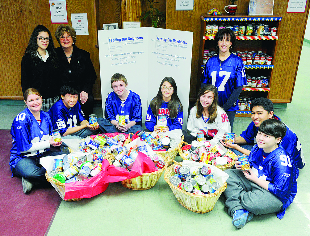 ‘SOUPER’ DAY—Students at St. Rita’s School on Staten Island got to dress in their New York Giants best Monday to celebrate their favorite football team’s advancement to the Super Bowl. They also brought in 334 cans of soup to help the Archdiocese’s Feeding Our Neighbors campaign. Above, from left in back row, are:  eighth-grader Farah Al-Hayek; principal Adele Kosinski; and Janet Weingarten, administrative assistant. Front row:  Donna Schuler, preschool assistant; and seventh-graders Matthew Montelibano, Ciran Farley, Francesca Lamberti, Madison Johnson, Jose Gerardo Delrosario and Matthew Mouton.