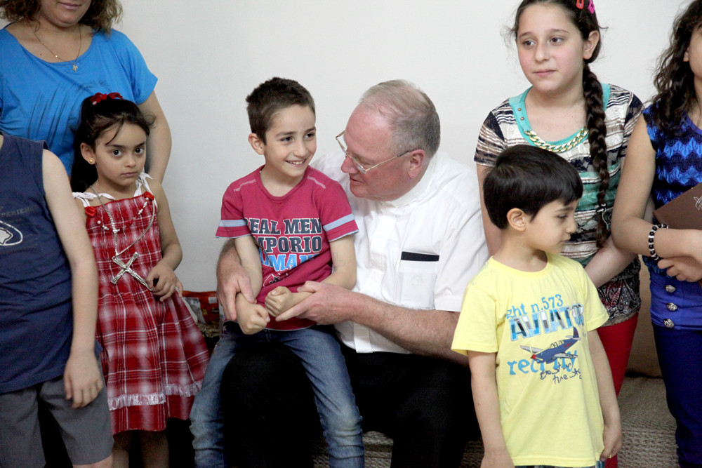 FAST FRIENDS—Cardinal Dolan greets children of refugee families May 6 at the convent of Franciscan Missionaries of Mary in Amman, Jordan, where he and Bishop William Murphy of Rockville Centre celebrated Mass in the convent chapel and then had dinner with the sisters and families there.