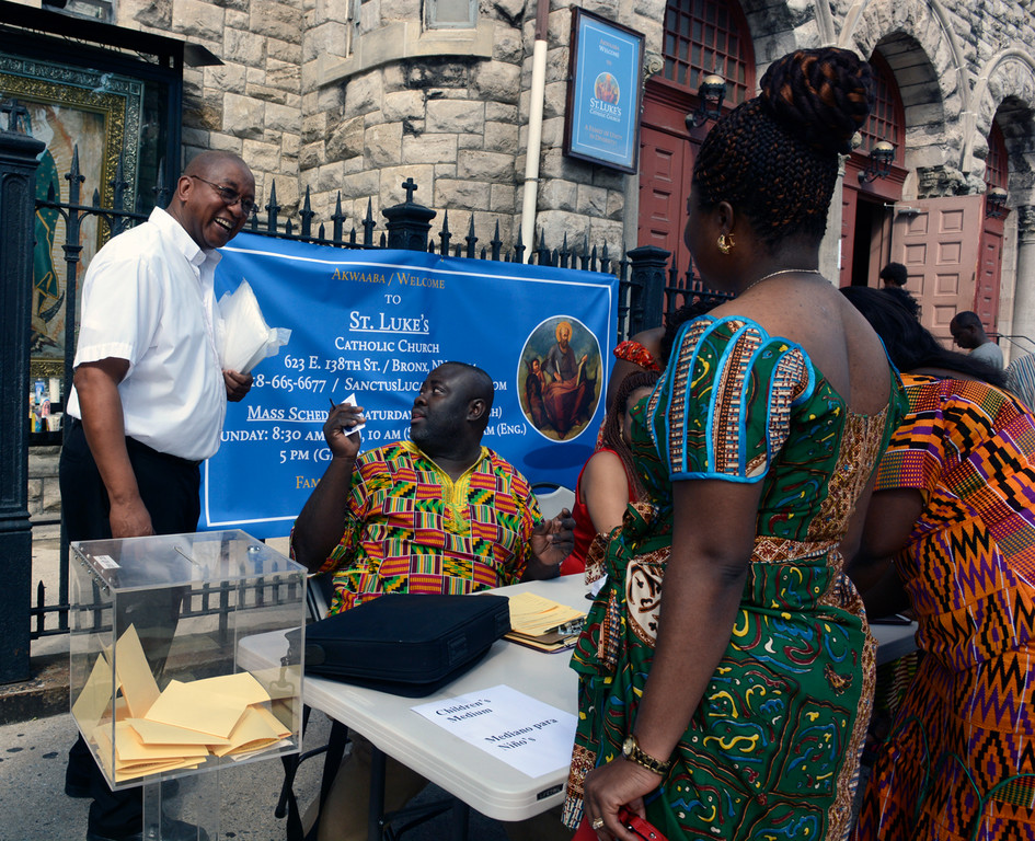 Ghanaian Catholics receive a gracious welcome to St. Luke’s parish in the Bronx at a registration table outside the church on 138th Street Aug. 2. Standing at far left is Brother Tyrone Davis, C.F.C., director of the archdiocesan Office of Black Ministry.