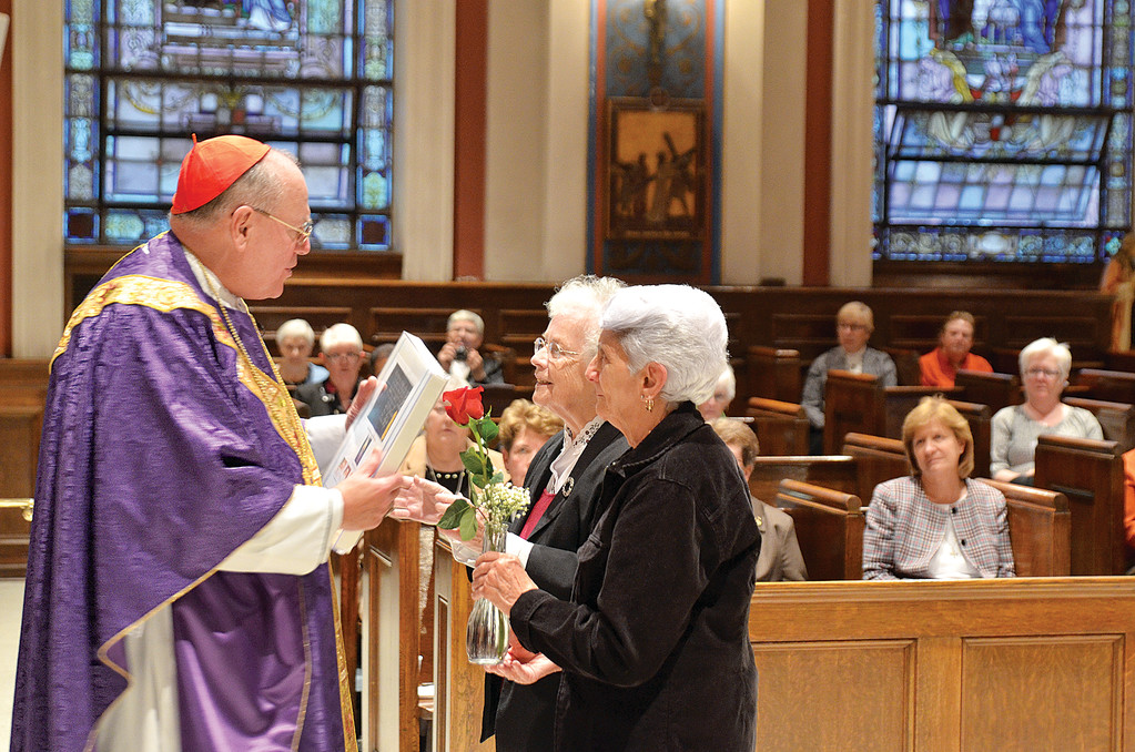 Gloria Pace, a friend of the congregation, carries a rose in memory of deceased sisters, and Sister Kathleen Sullivan, O.P., chancellor of Dominican College, brings up articles of incorporation, during the offertory.