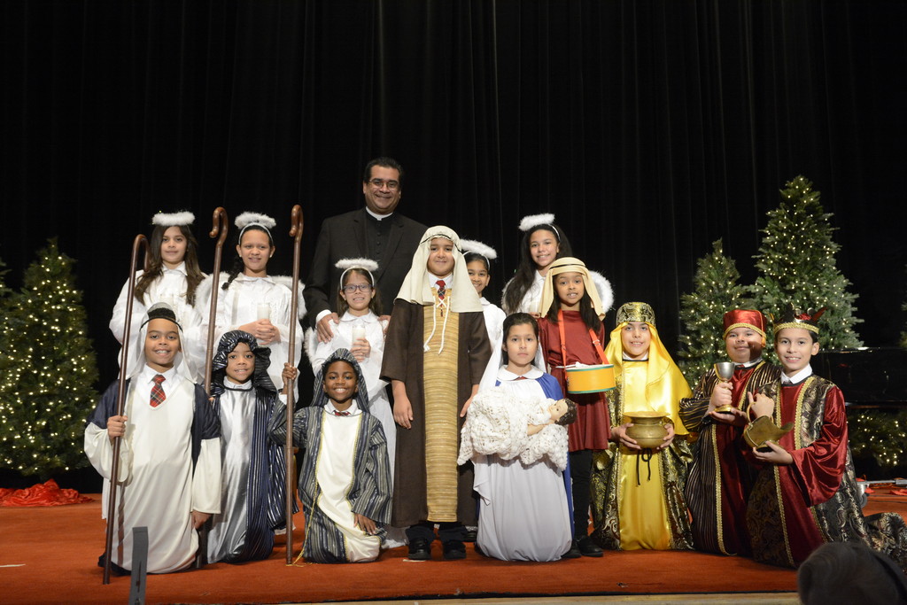 Father Eric Cruz, pastor of St. John Chrysostom parish in the Bronx, stands with students from St. John Chrysostom School following the 71st annual Cardinal’s Christmas Luncheon at the Waldorf Astoria on Dec. 5.