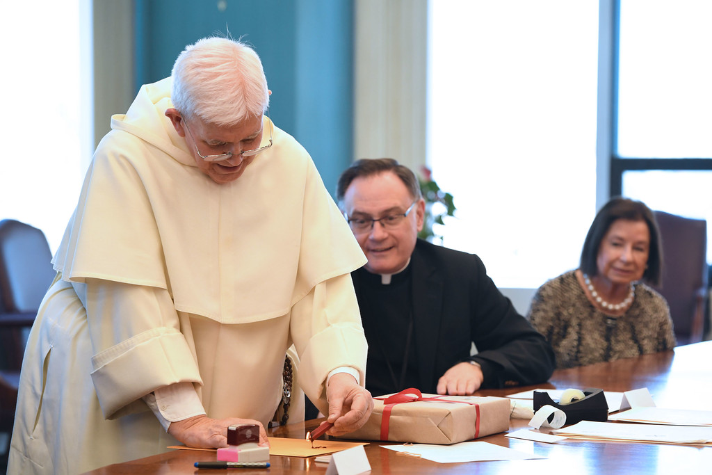 Father Gabriel O’Donnell, O.P., drops sealing wax onto an envelope with Msgr. Robert Hospodar and Valerie Mastronardi watching as the archdiocese closed its cause and mailed documents for officials in Rome to consider in the canonization cause of Father Paul Wattson, S.A.