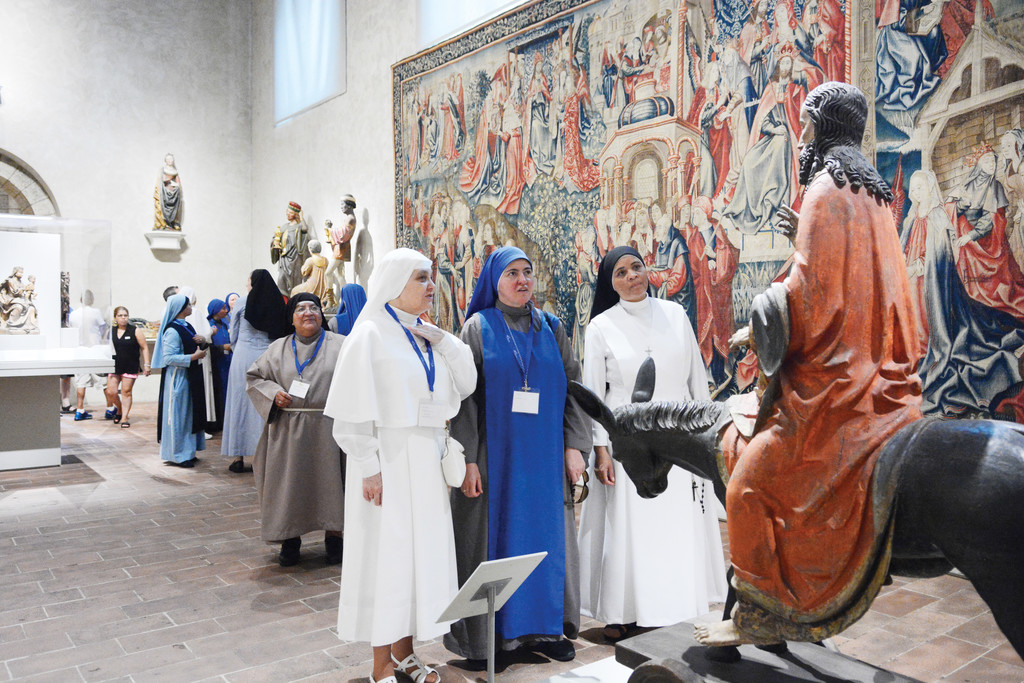 Three sisters admire the 15th-century German “Palmesel” statue of Jesus on a donkey re-enacting Christ’s entry into Jerusalem during their visit to The Cloisters in Manhattan July 22.