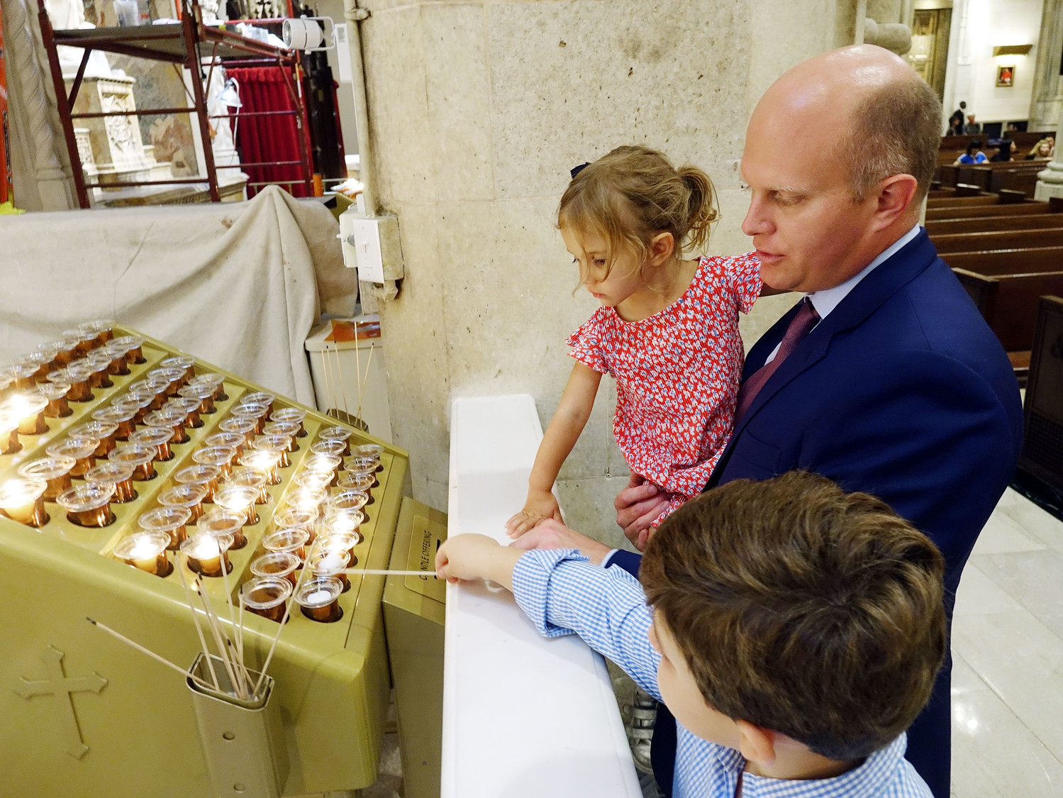 A curious Lillie Seton Lamb, 3, a descendent of Mother Seton, watches as her brother George lights a candle at the altar under the guidance of their father, Seamus Lamb.