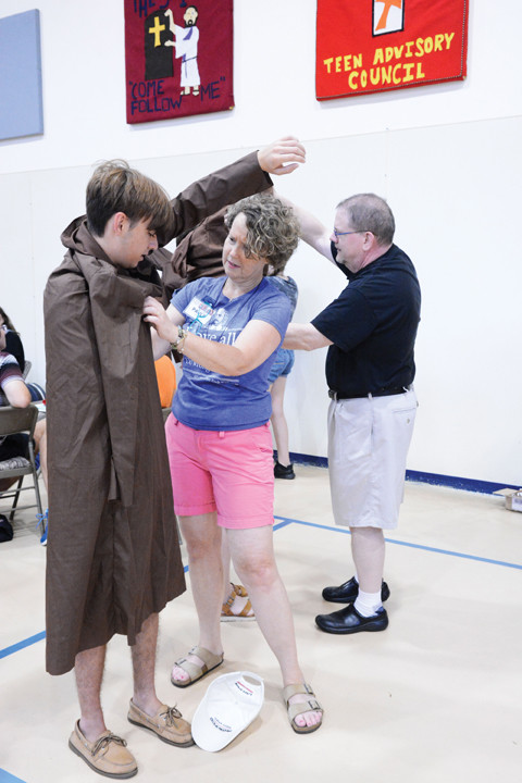 BLESSED SOLANUS ON STAGE—Cast member Nate Rosengrant, 16, tries on his costume with assistance from Paula Stuckart in St. Genesius Gymnasium at the Capuchin Youth & Family Ministries campus in Garrison July 30. The teen from Middletown, Conn., is one of 23 young people performing Friday, Aug. 3, in “Solanus: Blessed in America, The Story of Blessed Solanus Casey, O.F.M. Cap.” as part of the six-day Catholic Literature & Arts Summer Program overnight retreat.