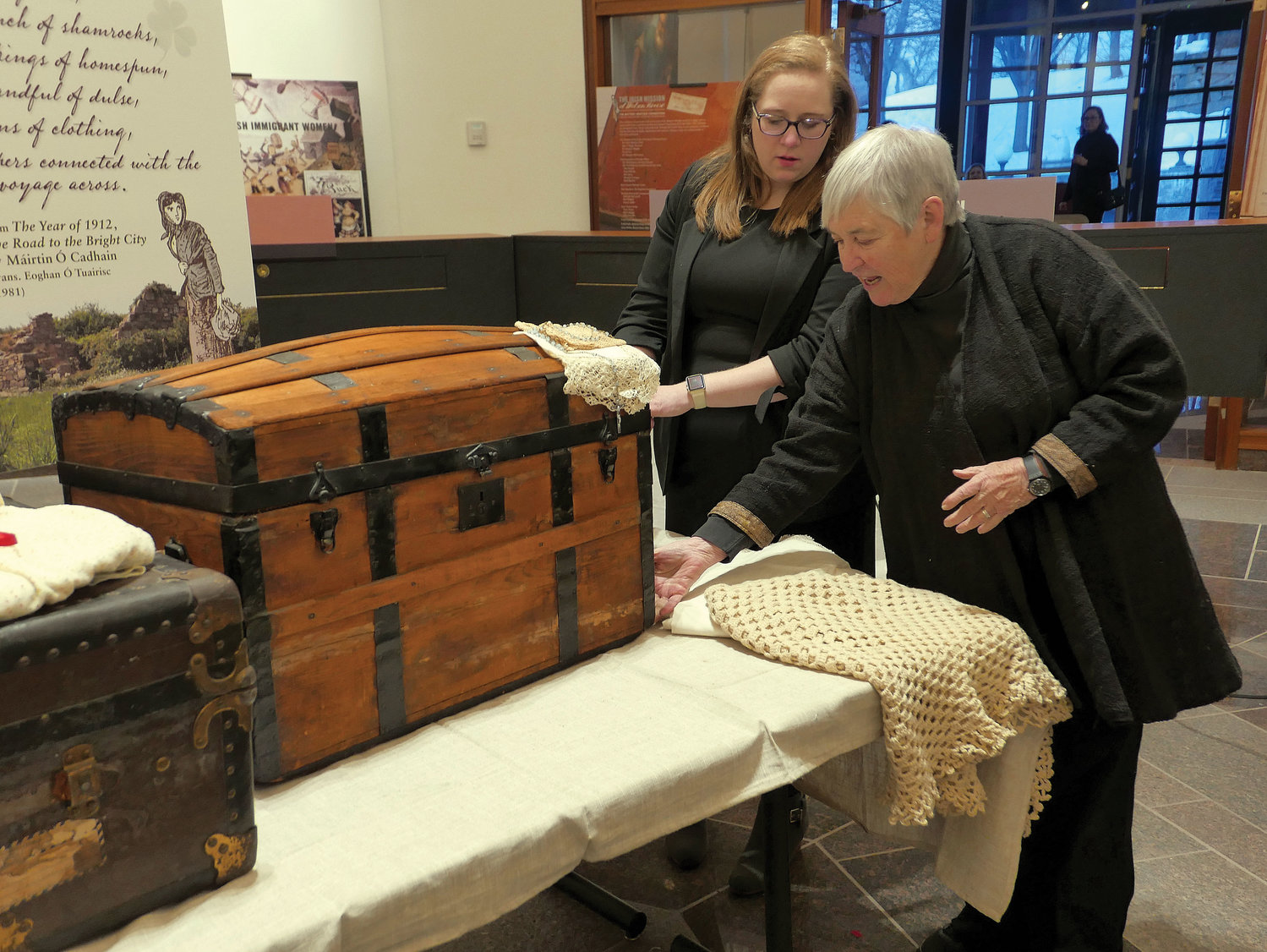 A photo exhibit of the Irish Mission at Watson House opened March 7 in the Archives Building at St. Joseph’s Seminary in Dunwoodie. Dr. Maureen Murphy, featured speaker at the exhibit opening touches a trunk used by her paternal grandmother, Martha Thompson, when she emigrated from Ireland in 1900. With Dr. Murphy is Kate Feighery, archdiocesan archivist.