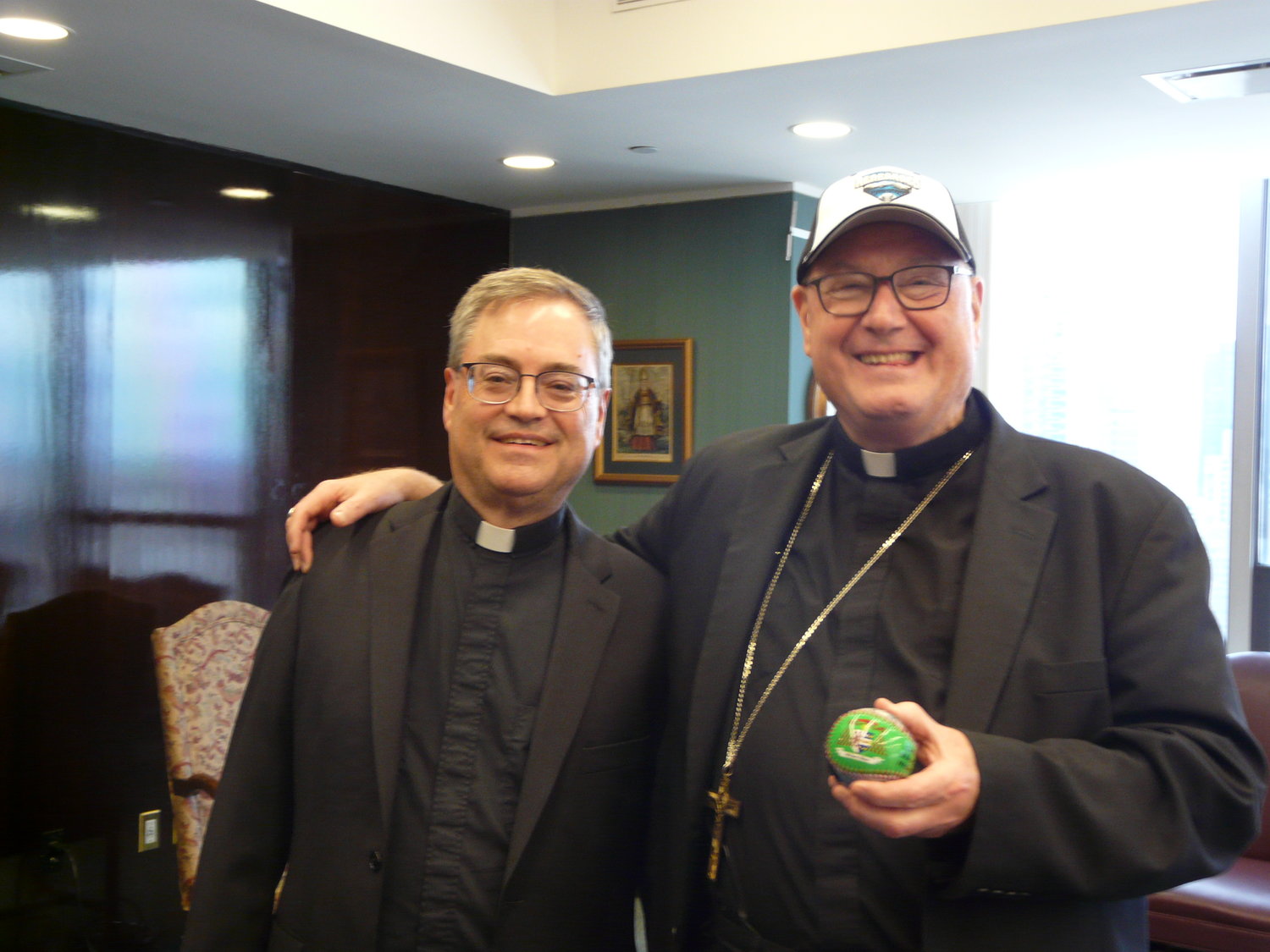 Cardinal Dolan and Father Michael McLoughlin, the pastor of St. Columba parish in Hopewell Junction, have already started to cheer for Catholic Education Night at Dutchess Stadium in Wappingers Falls, Monday, June 17, where the hometown Hudson Valley Renegades will play the Lowell Spinners in a minor league baseball contest. The cardinal holds a ball with a logo of St. Patrick's Cathedral to be given free to the first 2,500 fans to enter the stadium.
