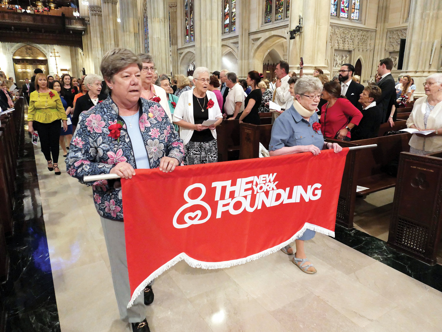 Sisters of Charity Donna Dodge, S.C., left, and Jane Iannucelli, S.C., carry a banner in procession for a Mass Cardinal Dolan celebrated in honor of the New York Foundling’s century and a half of service June 6 at St. Patrick’s Cathedral.