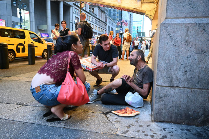 DINNER COMPANIONS—Felipe, right, sits outside Grand Central Terminal in Manhattan as he visits with two volunteers from Catholic NYC’s homeless outreach mission, Sheyla Curtis and Dan McGarry, who brought him dinner Aug. 21. An endeavor of the archdiocesan Young Adult Outreach Office, the group gathers monthly at Grand Central’s main concourse to seek out those in need.