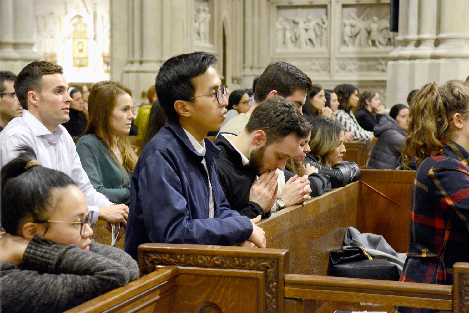 Young adults kneel in prayer during Eucharistic adoration preceding the Young Adult Mass celebrated by Cardinal Dolan at St. Patrick’s Cathedral.