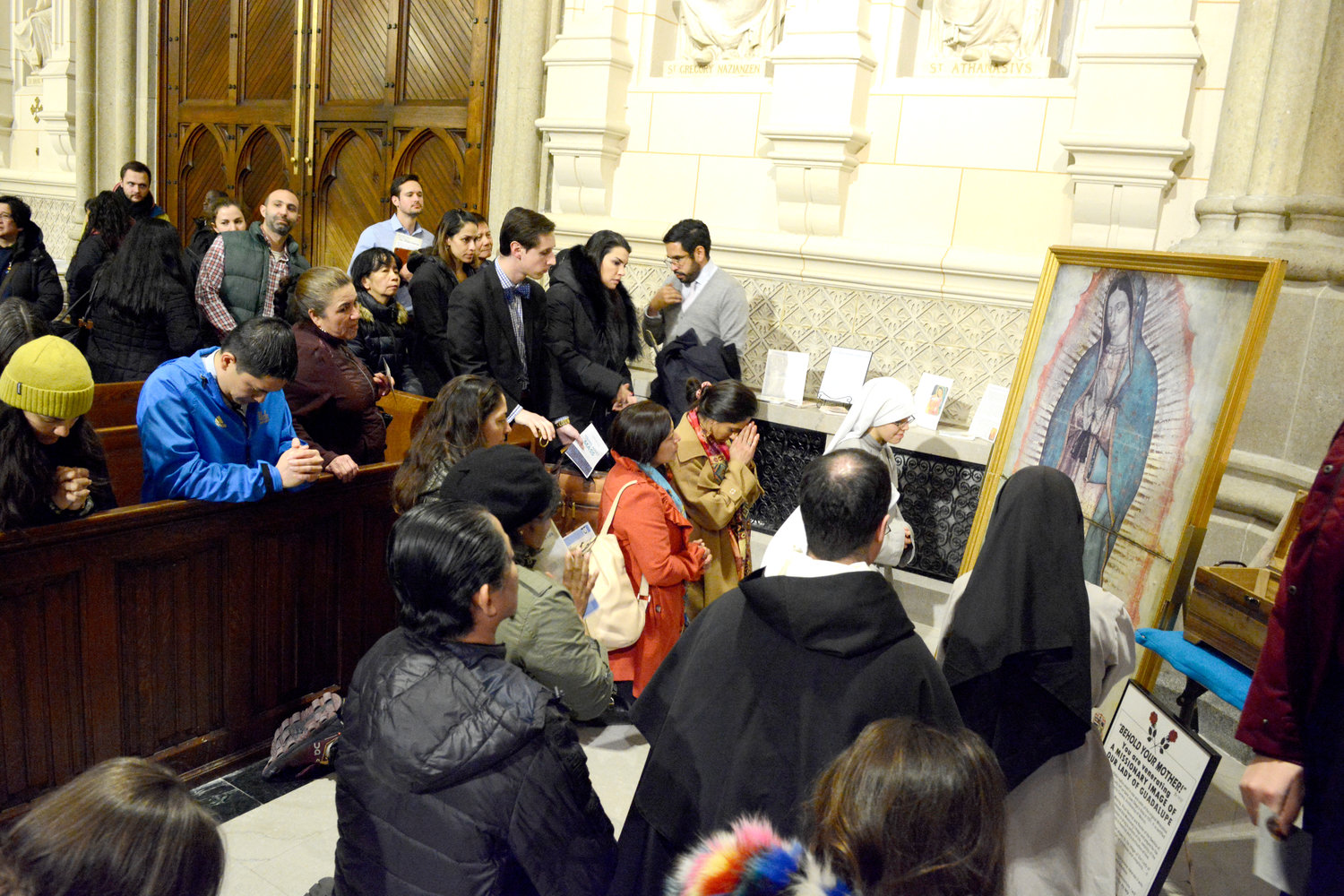 PIDIENDO POR LA INTERCESIÓN DE NUESTRA SEÑORA—Jóvenes adultos oran ante una imagen misionera de Nuestra Señora de Guadalupe después de la Misa de Jóvenes Adultos que el cardenal Dolan celebro el 4 de marzo en la Catedral de San Patricio.