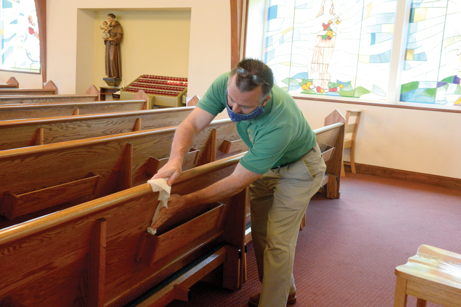 Usher Jim Banville wipes down a pew following Mass.