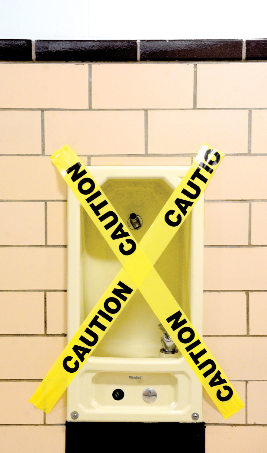 Tape crisscrossing a water fountain indicates it will be out of commission out of an abundance of caution.
