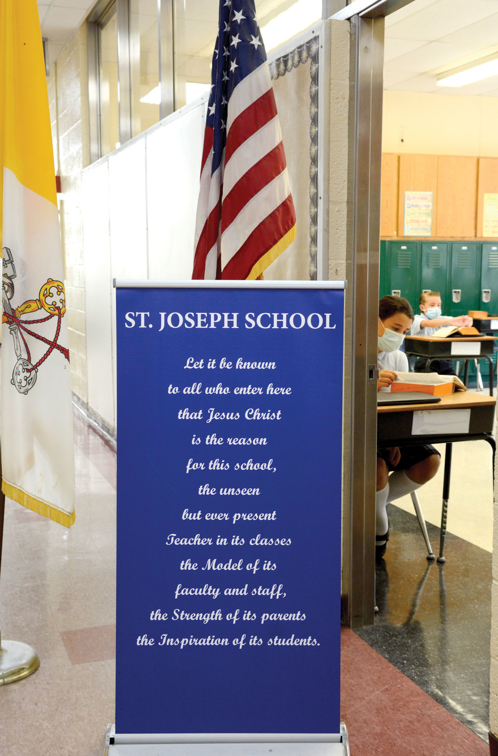 The school’s adherence to Catholic identity is showcased through an inspirational banner placed near the Vatican and American flags.