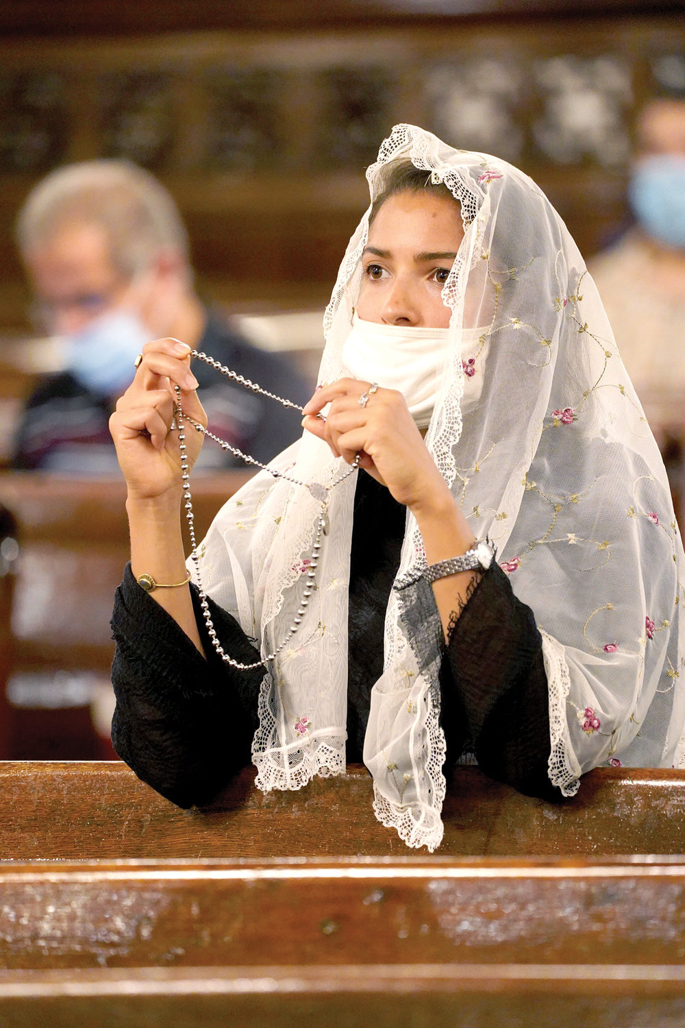 A woman prays the Rosary before the prayer service.