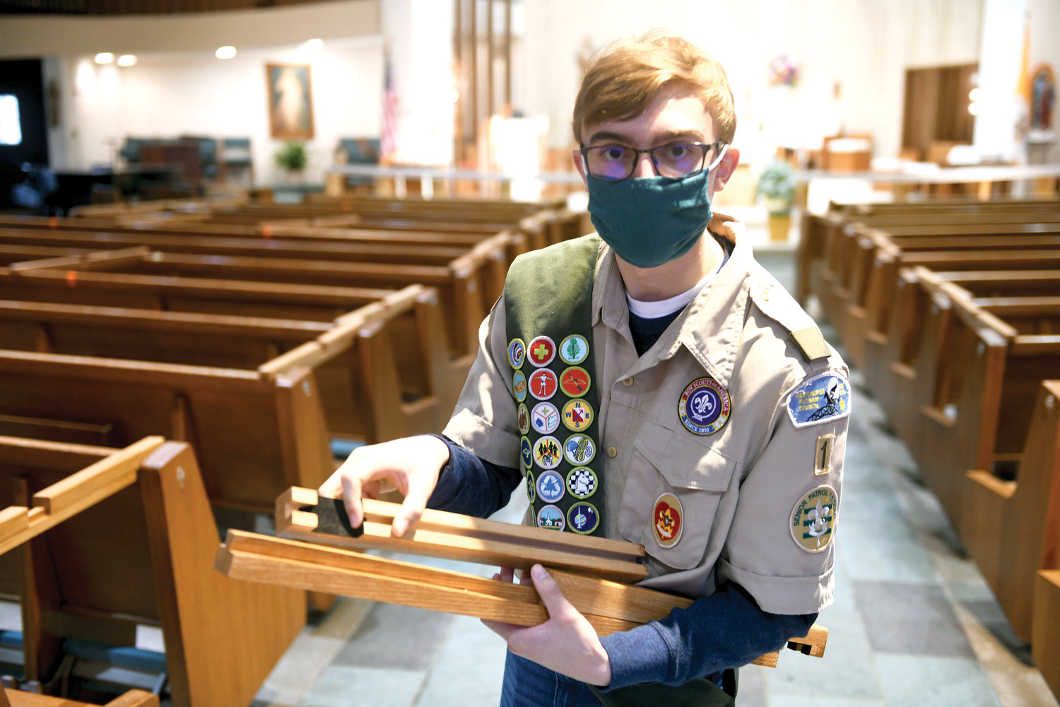 Boy Scout Anthony Decina holds an adjustable rail pew divider he designed and built as part of his comprehensive Eagle Scout project to help his parish church, St. Anthony of Padua in West Harrison, comply with social distancing measures during the Covid-19 pandemic.