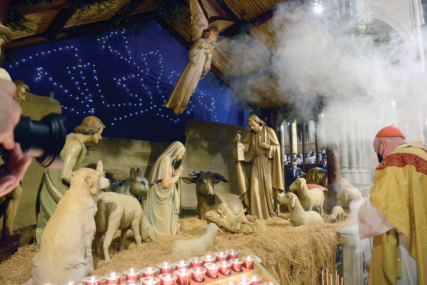 A SAVIOR IS BORN—At Christmas Midnight Mass in St. Patrick’s Cathedral, Cardinal Dolan kneels in prayer before the creche as incense wafts upward. With Mary and Joseph close by, the infant Jesus is also surrounded by animals in the serene depiction.