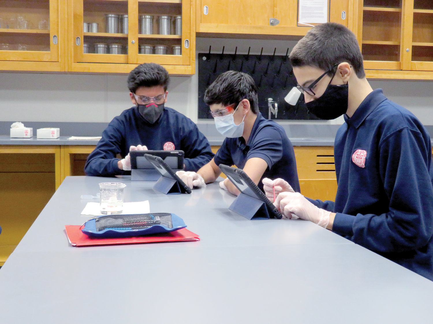 Students at John F. Kennedy Catholic Preparatory School in Somers are divided into two cohort groups that alternate weeks of in-person study with virtual instruction at home. Sophomores Jalen Alvarez-Vasquez, Ellis Kennedy and Lukas Gojcaj complete a solubility chemistry laboratory experiment.