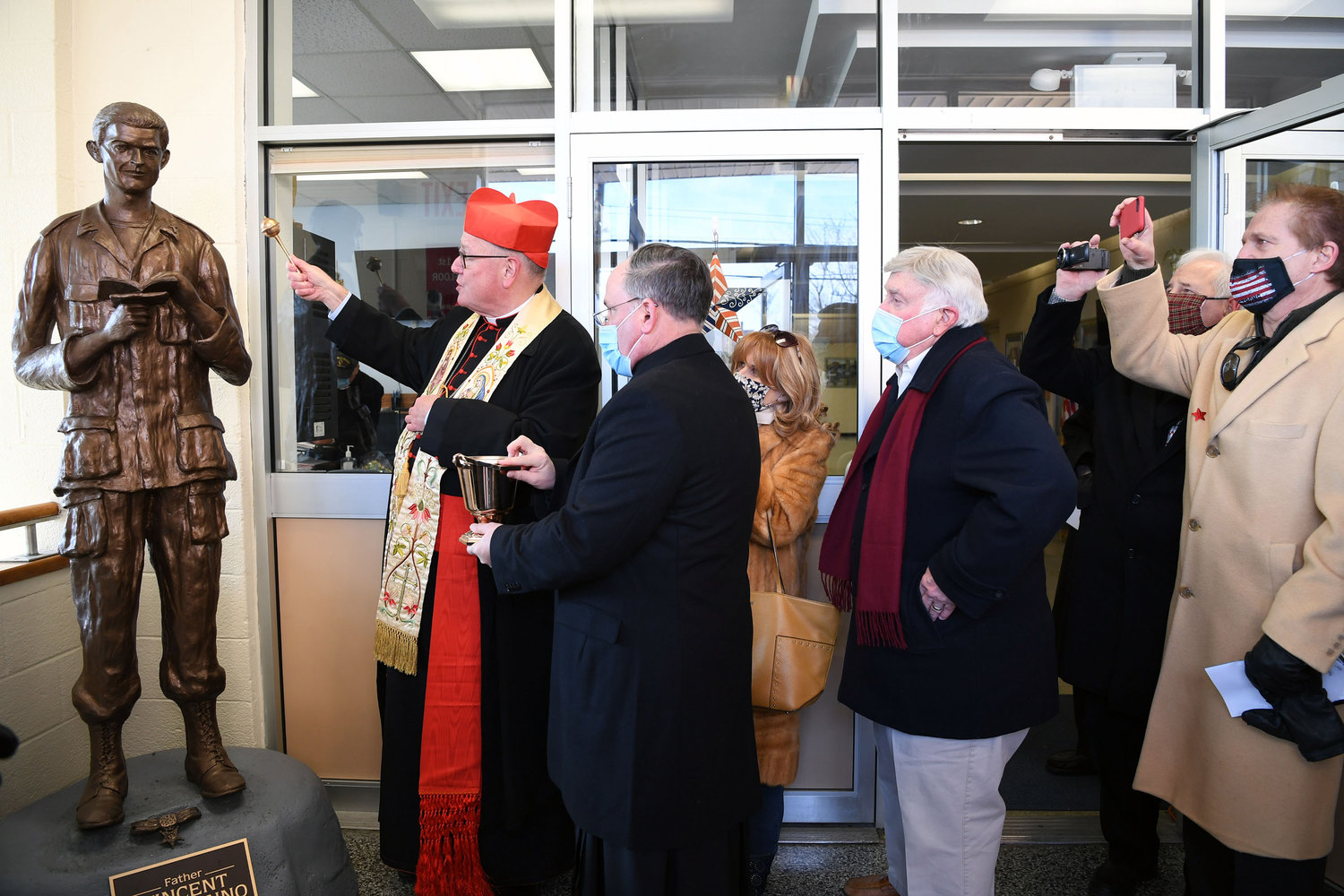 Cardinal Dolan blesses a statue of Father Vincent Capodanno, M.M., in the lobby of Father Vincent Capodanno Catholic Academy on Staten Island Jan. 21. Cardinal Dolan, who dedicated the academy in the same ceremony, is assisted by Father Michael Martine, pastor of Holy Rosary parish on Staten Island. The academy opened in September after the merger of Holy Rosary and St. Adalbert schools for the 2020-2021 school year.