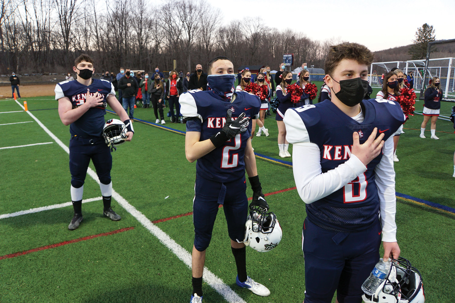 Bobby Piesco, Francisco Rivera and Carmine Calandrello stand for the National Anthem before John F. Kennedy Catholic Preparatory School and St. Dominic High School kicked off the football season in Somers March 12.