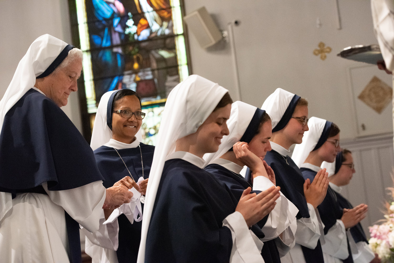 Mother Agnes and Sister Grace Dominic, S.V., the novice director, remove white cloth strips revealing the blue band in the habit of a newly professed sister.