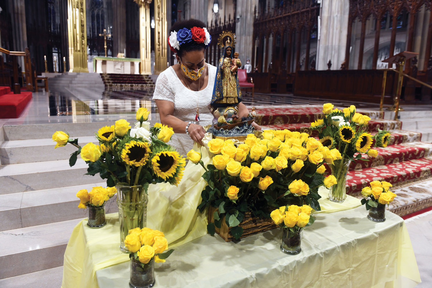 An organizer of the annual Our Lady of Charity del Cobre Mass prepares a floral and statue display before the Sept. 5 Mass at St. Patrick's Cathedral. Our Lady of Charity del Cobre is the patroness of Cuba. Story on page 3.