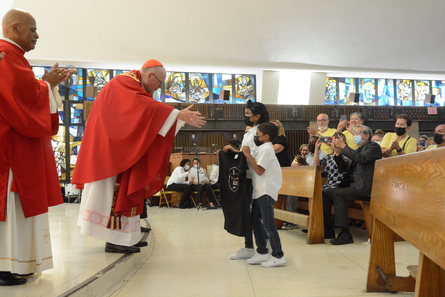Cardinal Dolan receives a centennial T-shirt at Mass.