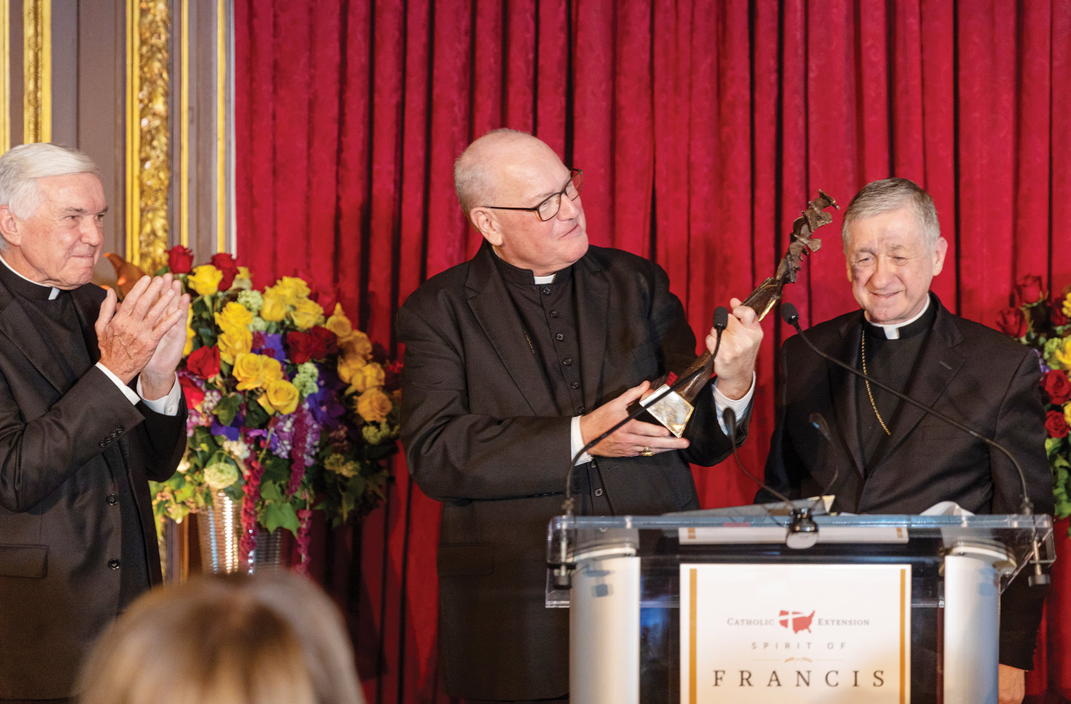 Cardinal Dolan accepts the Spirit of Francis honor Nov. 30 at the award dinner of Catholic Extension Society at the Metropolitan Club in Manhattan. At left is Father Jack Wall, president of Catholic Extension, and at right is Cardinal Blase J. Cupich of Chicago, who is chancellor of Catholic Extension. Cardinal Dolan was honored for his solidarity with the Church in Cuba and his “advocacy for the weak and marginalized.”