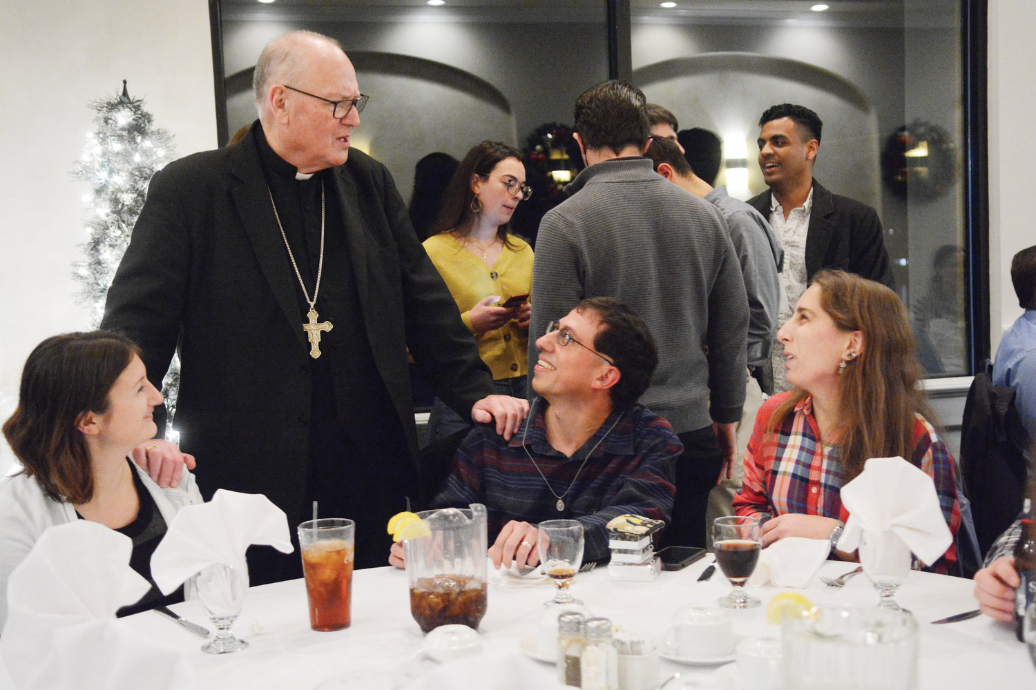 Cardinal Dolan speaks with Amanda Hallworth, and married couple Edward and Claire Abdallah, during Theology on Tap evening for Catholic young adults Dec. 16 at Four Brothers Restaurant in Mahopac.