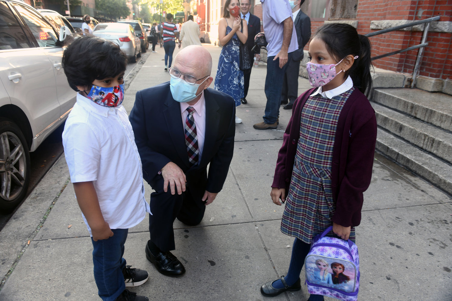 In September, Michael Deegan, superintendent of schools in the archdiocese, kneels to greet young students and the new academic year outside the Academy of St. Paul and St. Ann in East Harlem.