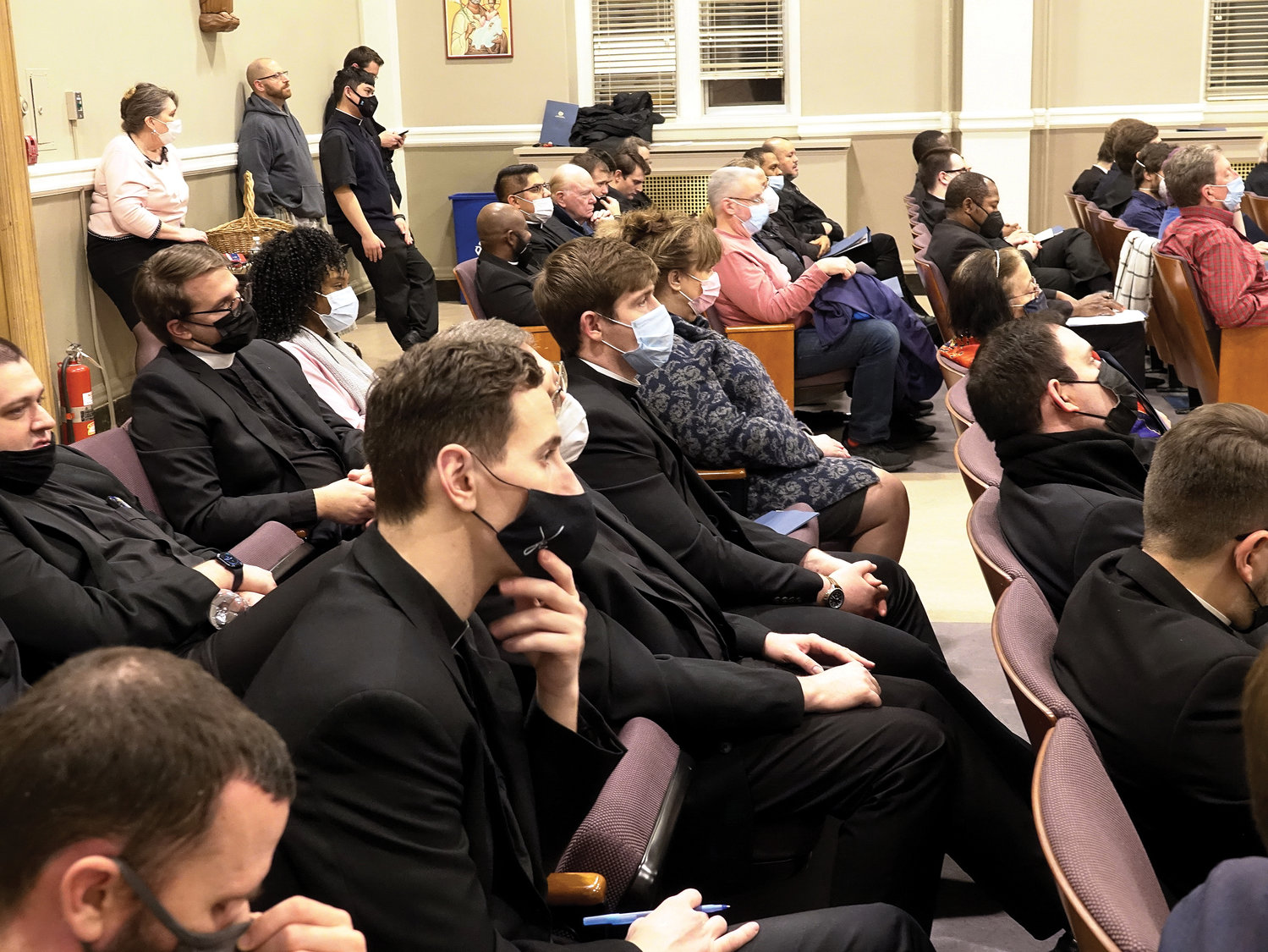 The large crowd, including many seminarians, listens closely to the talk.