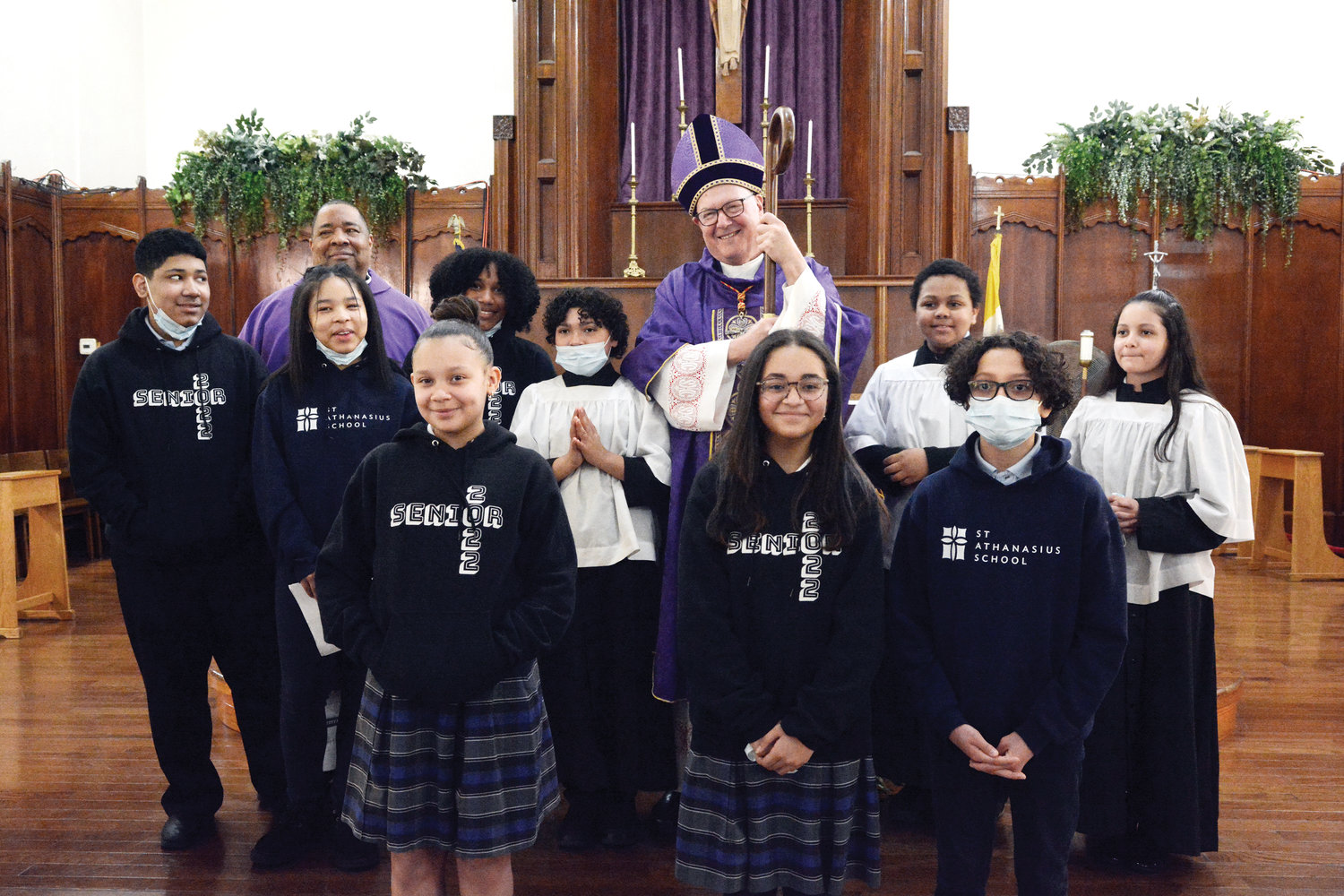 Students who assisted with the liturgy posed for a photo with the cardinal and Father Jose Rivas, pastor of St. Athanasius.