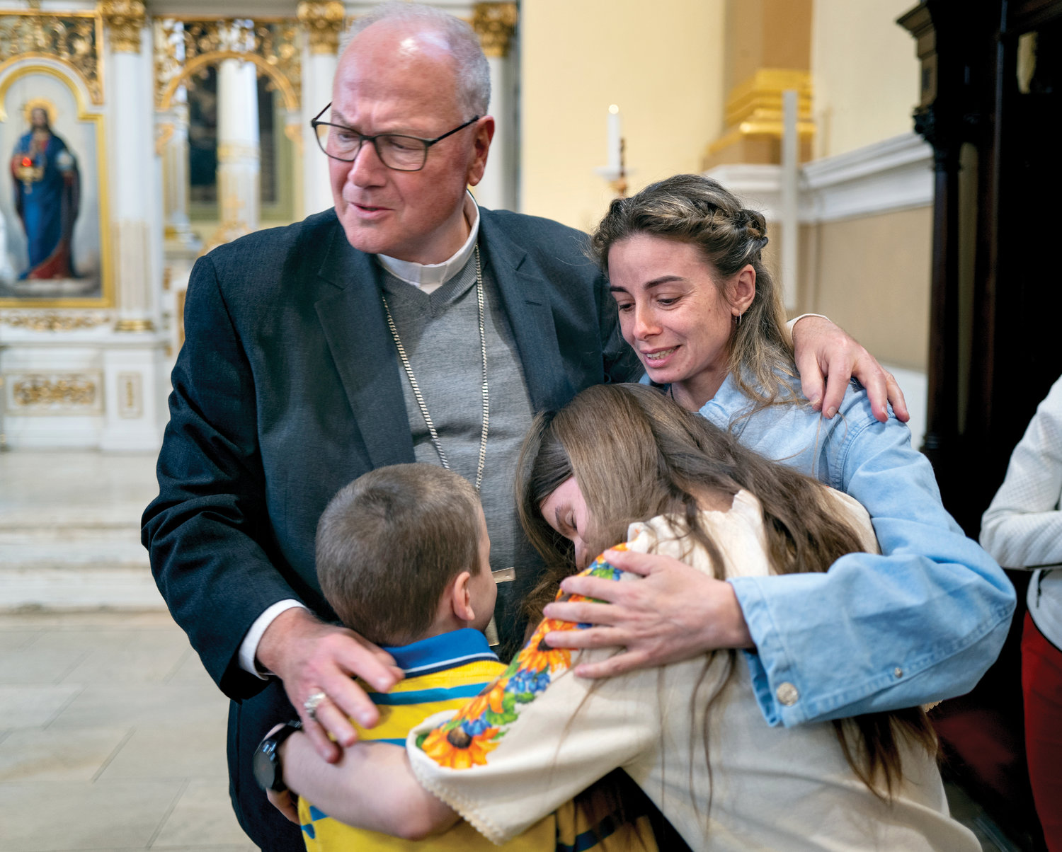 Cardinal Dolan embraces Katarina Leshenka of Kiev and two of her three children as he greeted Ukranian refugees at the Eparchy of Košice Slovak Greek Catholic Church  in Slovakia April 30. The cardinal led a New York Church delegation on a trip to Poland, Slovakia and Ukraine, where they met with refugees and saluted aid workers assisting them.