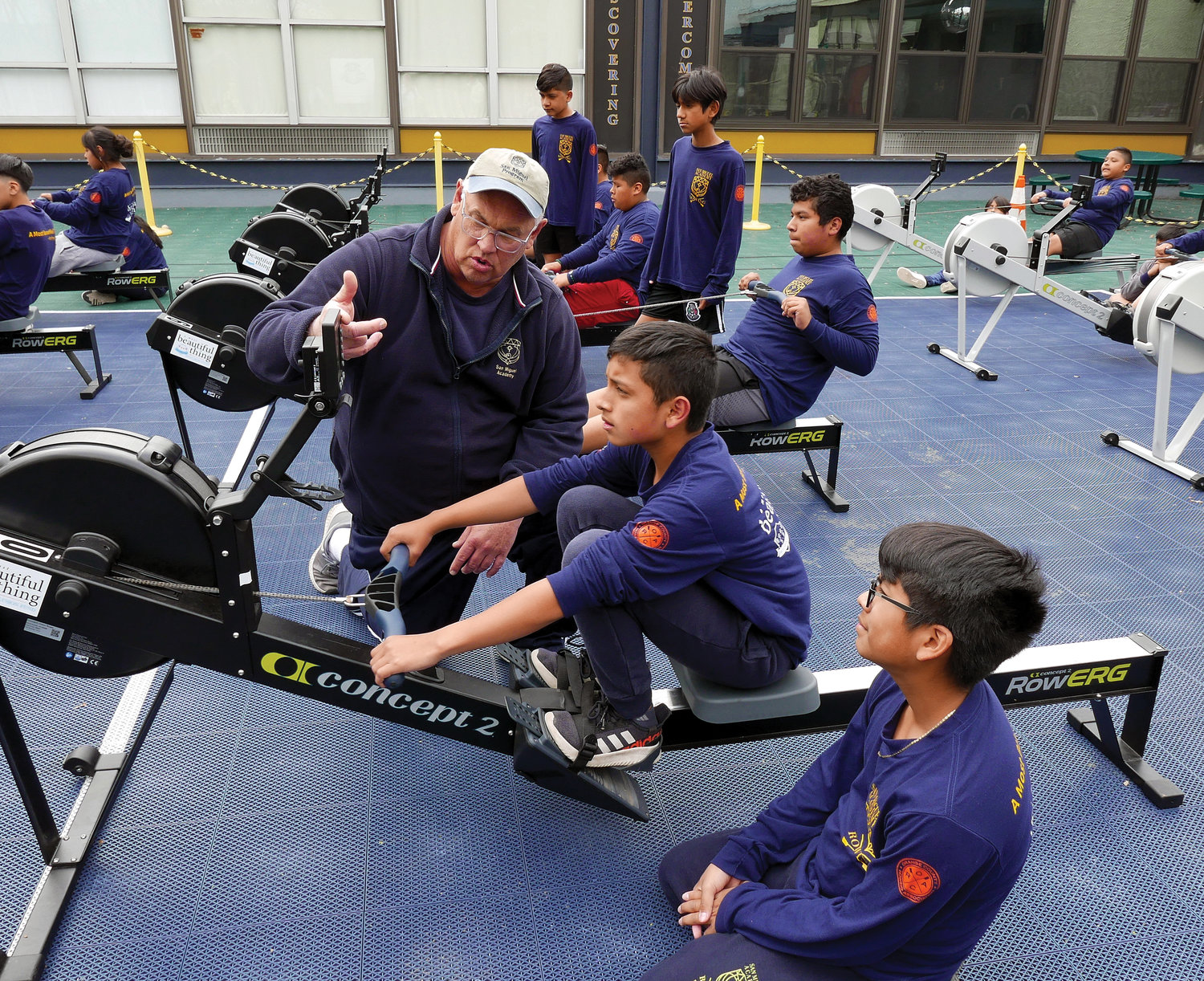 Father Mark Connell, executive director for San Miguel Academy and a coach for the rowing program, works with team members using the rowing machine at the academy in Newburgh.
