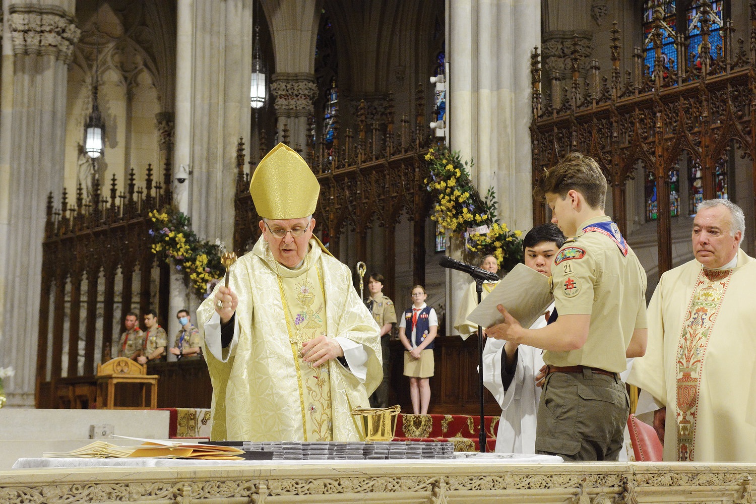 Auxiliary Bishop John O’Hara blesses the medals of faith he presented to Boy Scouts, Girl Scouts and adult leaders during Mass.