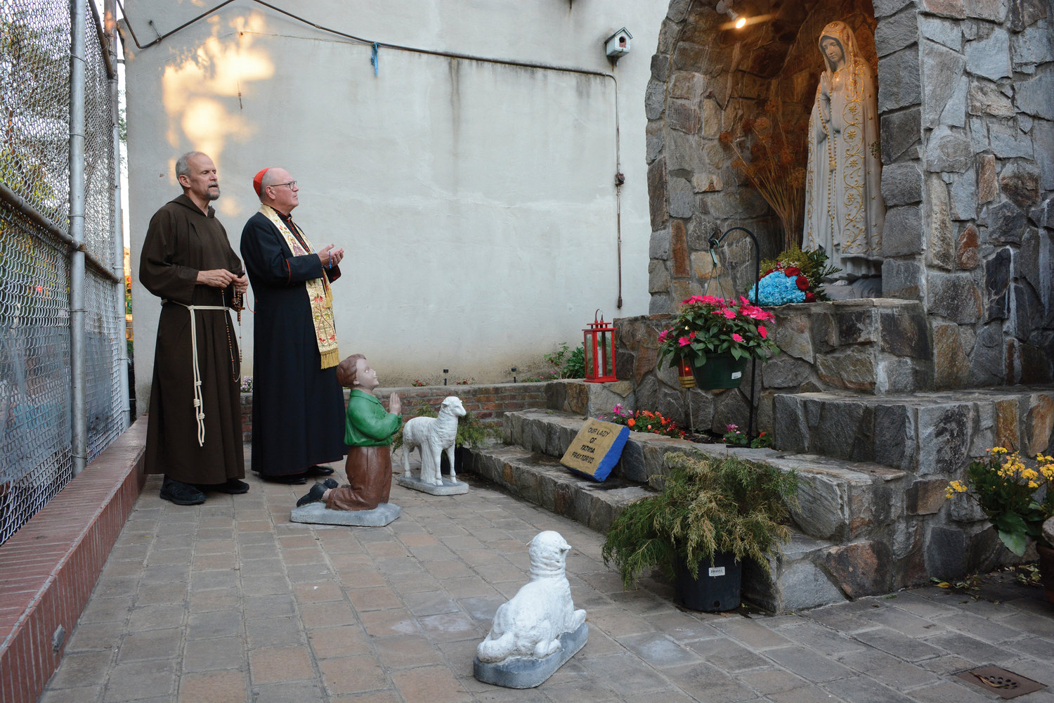 Cardinal Dolan and Father Thomas McNamara, O.F.M. Cap., pastor of Our Lady of Sorrows parish in Manhattan, pray the Rosary outdoors in the early evening May 31 at the parish’s Our Lady of Fatima Grotto.