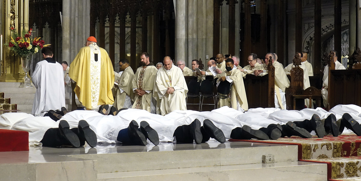 Those being ordained to the permanent diaconate June 18 lie prostrate in the sanctuary of St. Patrick’s Cathedral as Cardinal Dolan kneels in prayer during the Litany of Supplication.