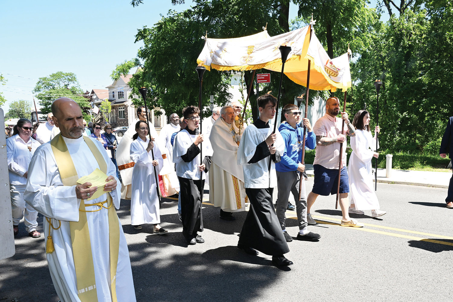 Father Arthur Mastrolia, pastor of St. Clare parish, Staten Island, far left, participates with his parishioners in a neighborhood-wide Corpus Christi procession that followed the 10 a.m. Mass he offered at the church June 19. Deacon Richard Mitchell, a permanent deacon of the parish, carries the monstrance that contains the Blessed Sacrament to the fourth altar station along the procession route.