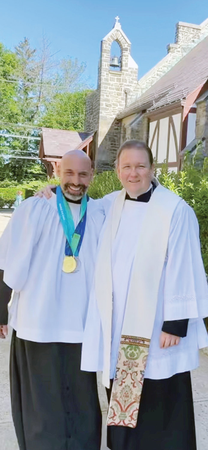 Paul Asaro wears the gold and silver medals he won last month in Florida at the 2022 Special Olympics USA Games in this photo with Msgr. Luke Sweeney, pastor of Immaculate Heart of Mary parish in Scarsdale, outside the church.