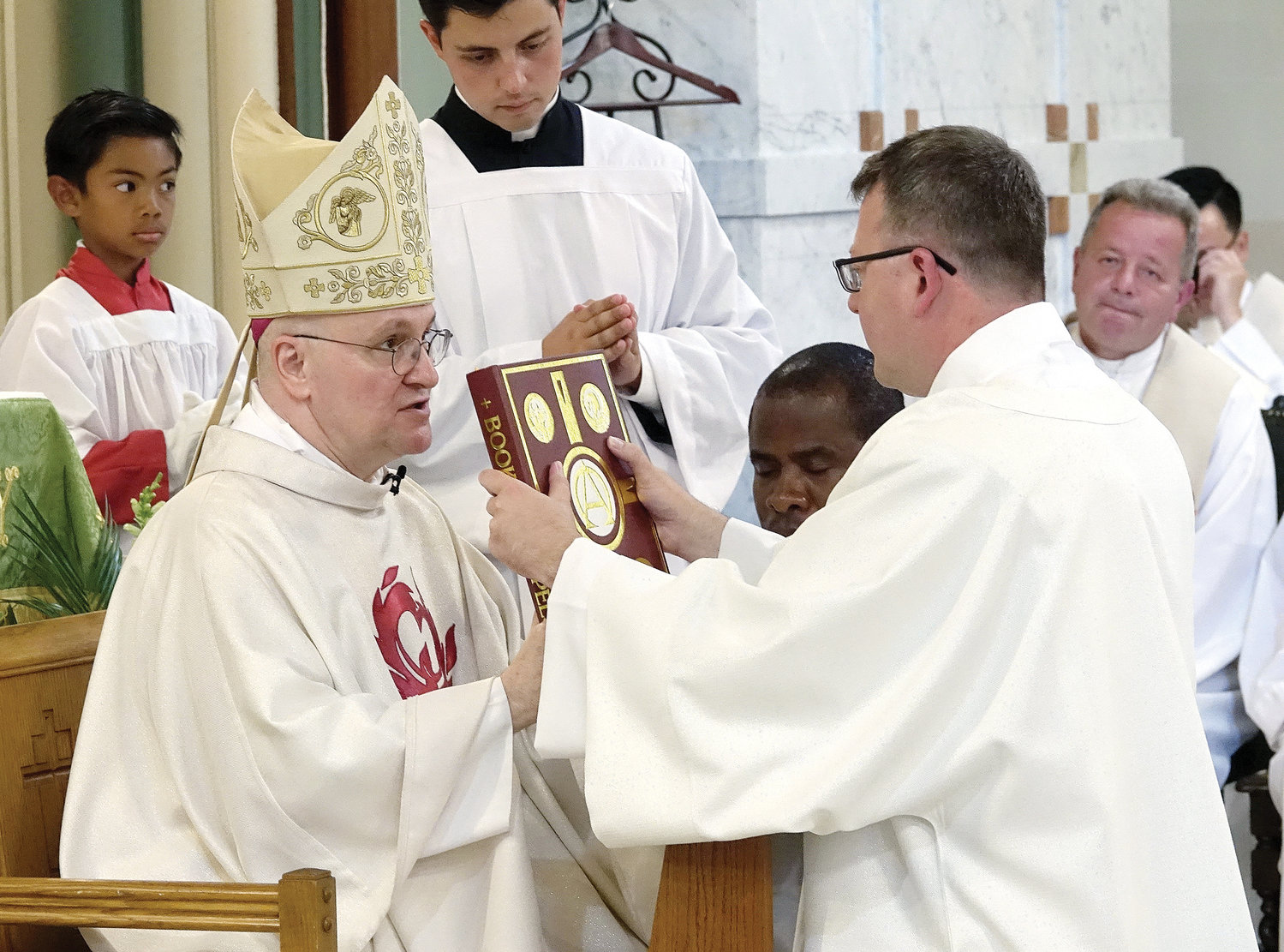 Auxiliary Bishop James Massa, rector of St. Joseph’s Seminary, Dunwoodie, presents Deacon Steven Neier, C.O., with the Book of the Gospels during the July 17 Mass at which he was ordained  to the transitional diaconate at St. Ann Church in Nyack.