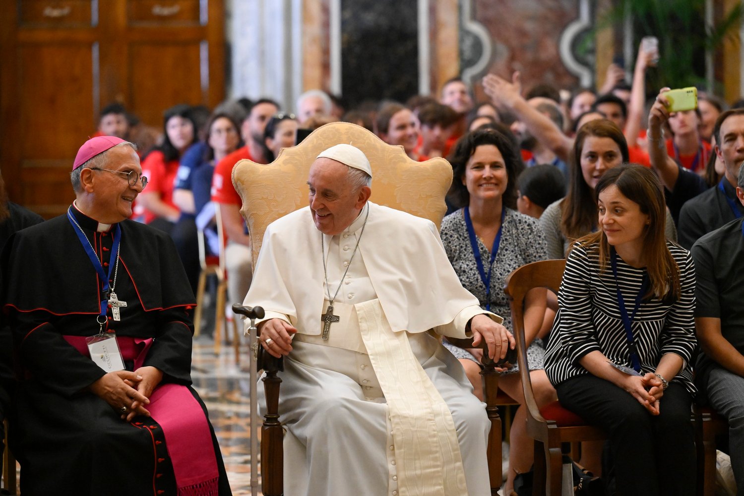 Pope Francis is seated next to an unidentified bishop as he leads an audience with young people participating in a summer camp program sponsored by Alpha International, at the Vatican Aug. 5.