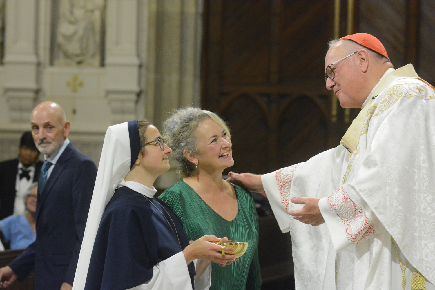 Cardinal Dolan speaks with Sister Caroline Caritas, S.V., as she presents offertory gifts during the Aug. 6 Mass for the perpetual profession of vows for the Sisters of Life at St. Patrick’s Cathedral. Sister Caroline Caritas is joined by her mother, Tracey Ingold.