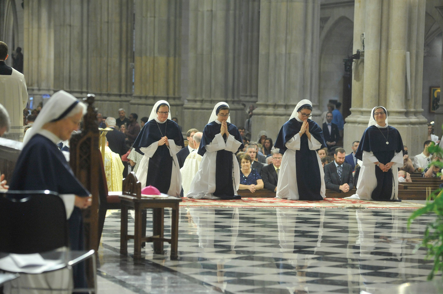 Kneeling in prayer in the sanctuary are, from left, Sister Lucia Christi, S.V.; Sister Caroline Caritas, S.V.; Sister Marie  Frassati, S.V.; and Sister Gemma Grace Marie, S.V. In the foreground at far left is Sister Agnes Mary Donovan, S.V., superior general of the Sisters of Life.