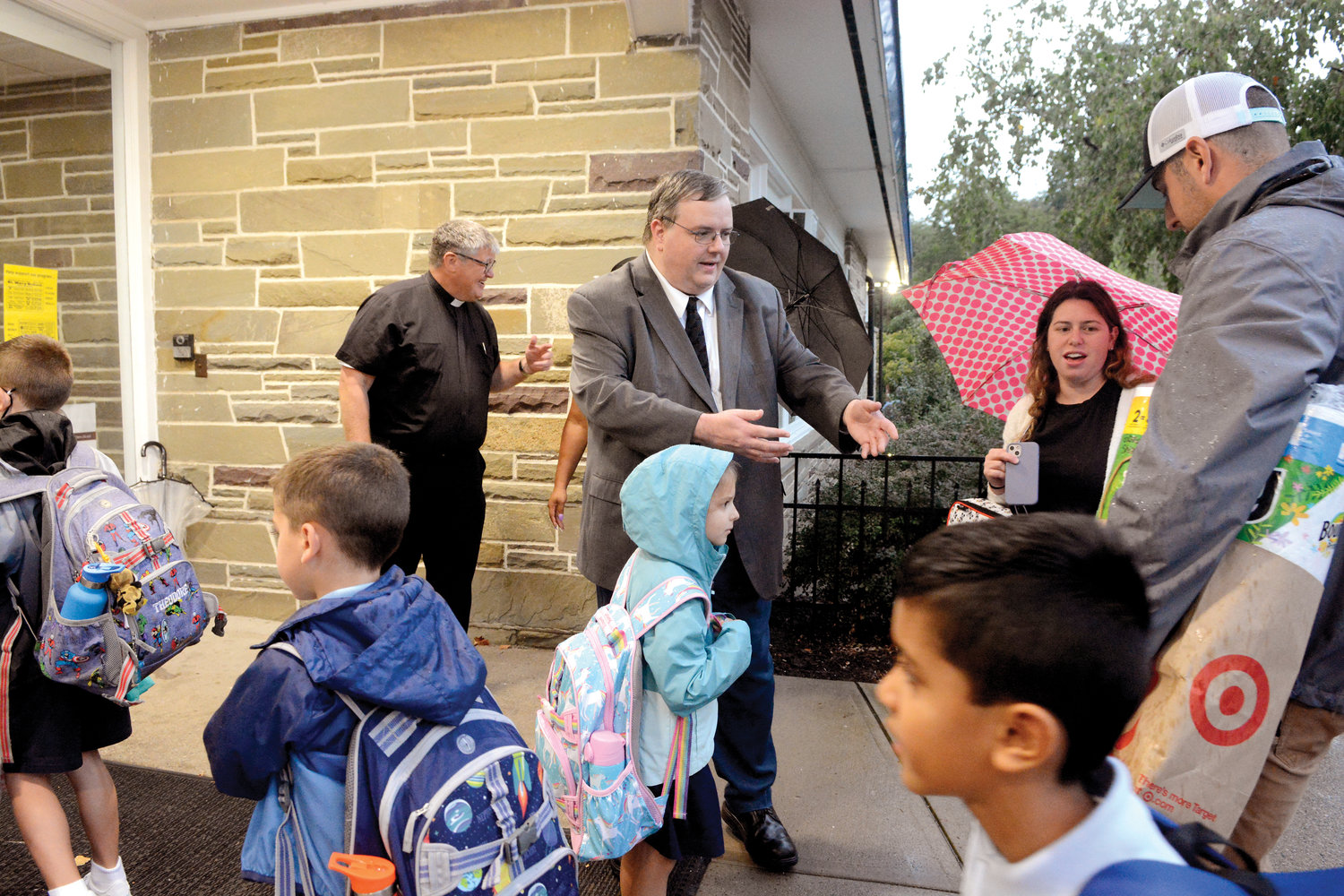 SCHOOL YEAR BEGINS—The wet skies did not deter students of St. Mary’s School in Fishkill on their first day of school Sept. 6. Above, principal Tom Hamilton gladly accepts supplies from parents dropping off their children near the entrance of the pre-K to grade school in Dutchess County. In the background, Father Joseph Blenkle, the pastor of St. Mary, Mother of the Church, joins the first-day activity.