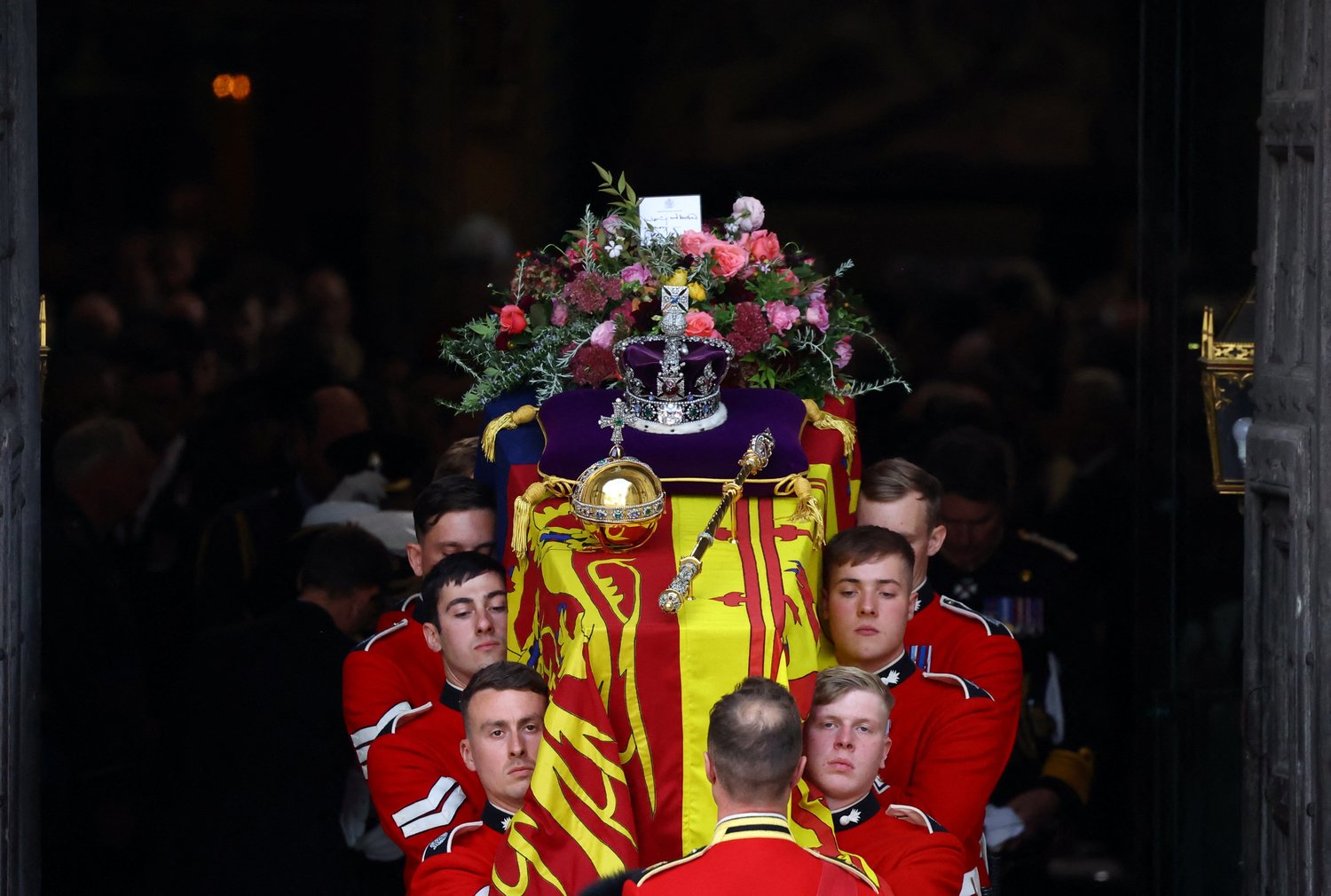 Pallbearers carry the casket of Queen Elizabeth II with the Imperial State Crown resting on top out of Westminster Abbey following her state funeral in London Sept. 19.