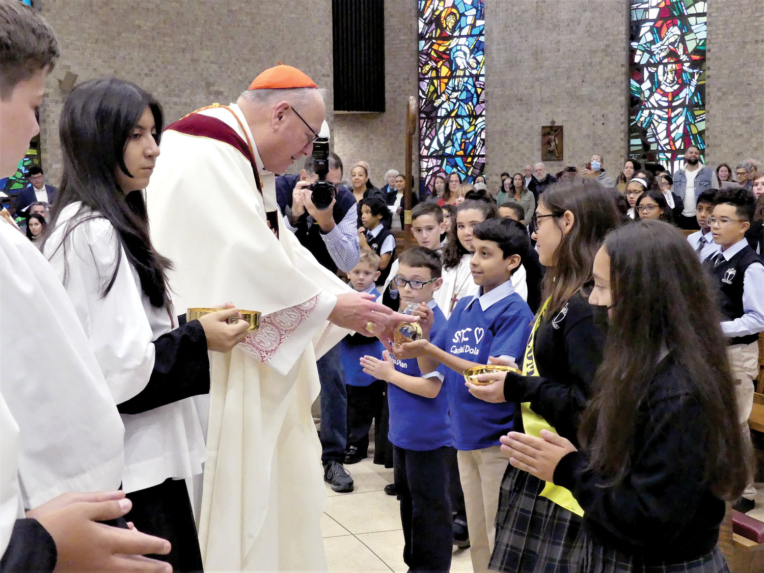 Cardinal Dolan receives offertory gifts from students at the Mass.